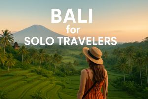 A solo female traveler wearing a sunhat looks over the lush Tegallalang Rice Terraces in Bali at golden hour, with Mount Agung in the background. White text reads Bali for Solo Travelers.